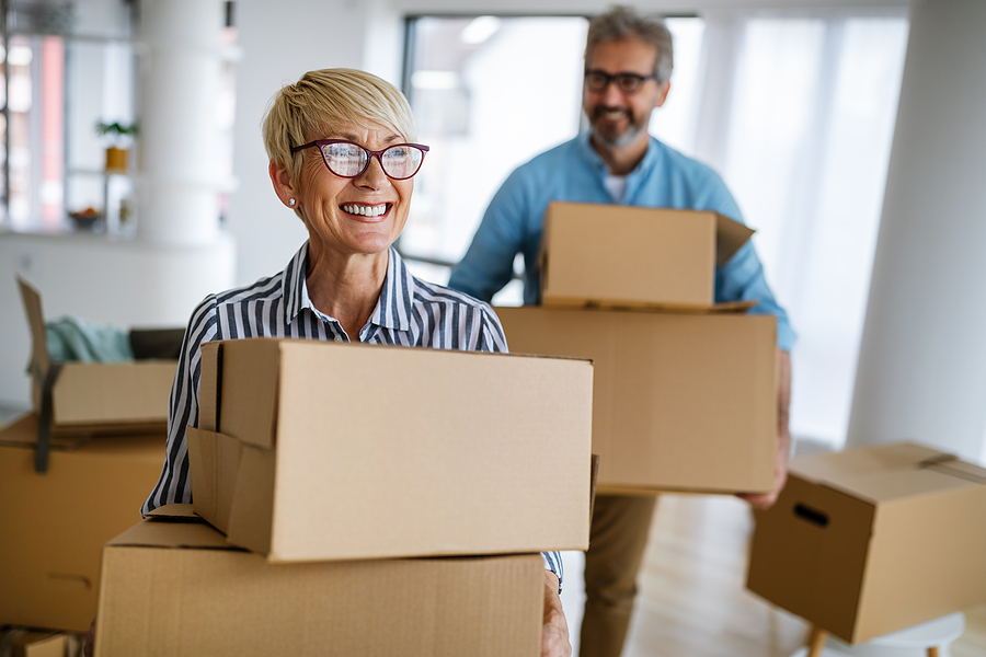 An older couple moving packing boxes in their home