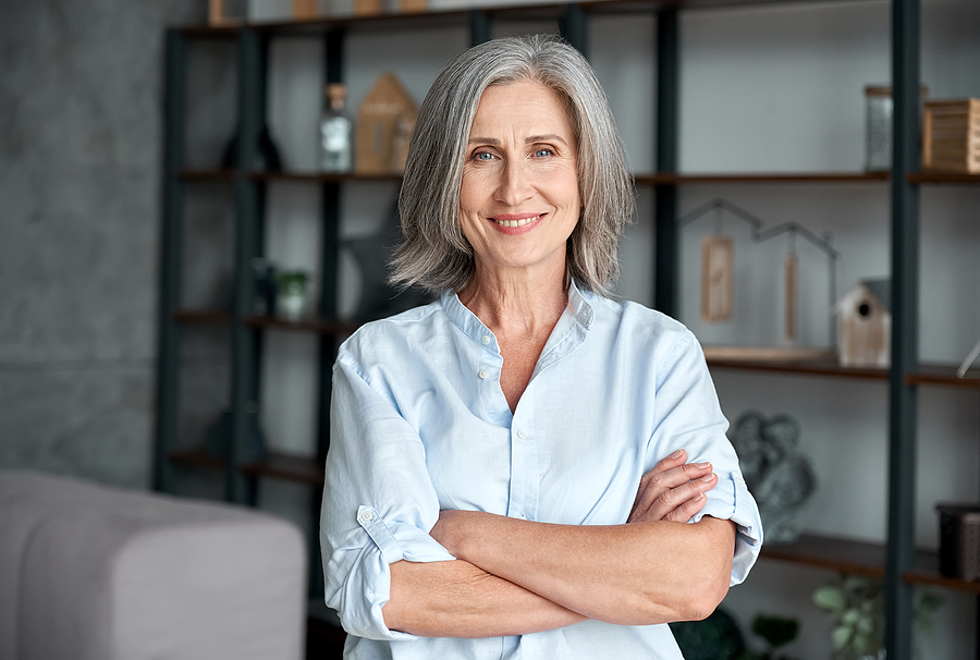 Smiling confident stylish mature middle aged woman standing at home office