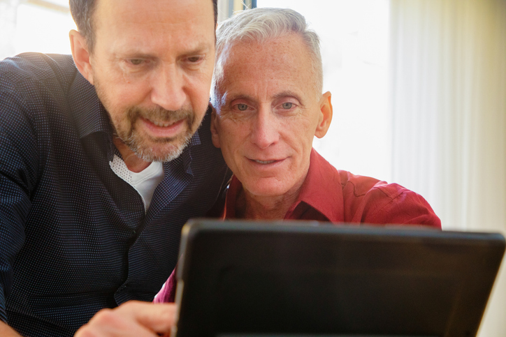 Senior gay couple looking closely at news on tablet
