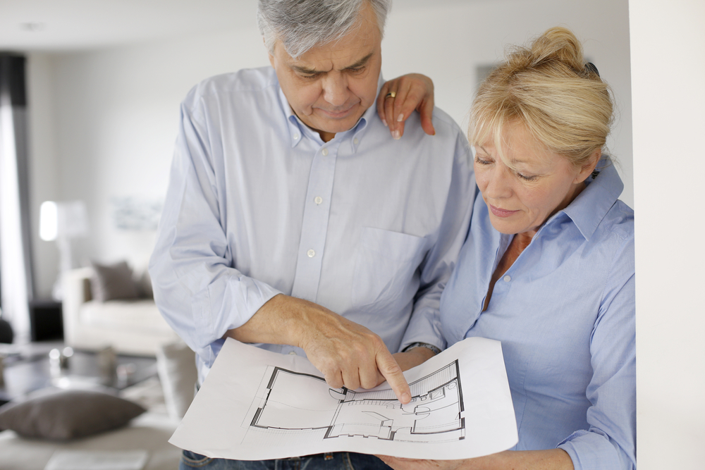 A senior couple look at floor plans for their home